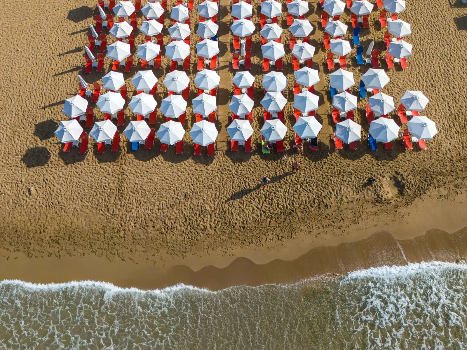 Rows of beach umbrellas and loungers seen from above on a Greek beach